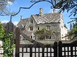 Large house opposite the church Large Cotswold stone mansion viewed through a wrought iron lynch-gate