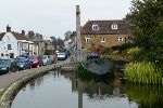 View over a pond and past a war meorial and then up a shopping street of low buildings