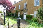 View across front garden to a brown sandstone Georgian-style building
