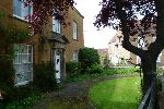 View across front garden to a brown sandstone Georgian-style building