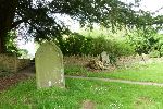 Gravestone under a spreading yew in the corner of the churchyard