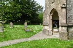 View past the church porch to a large Yew tree